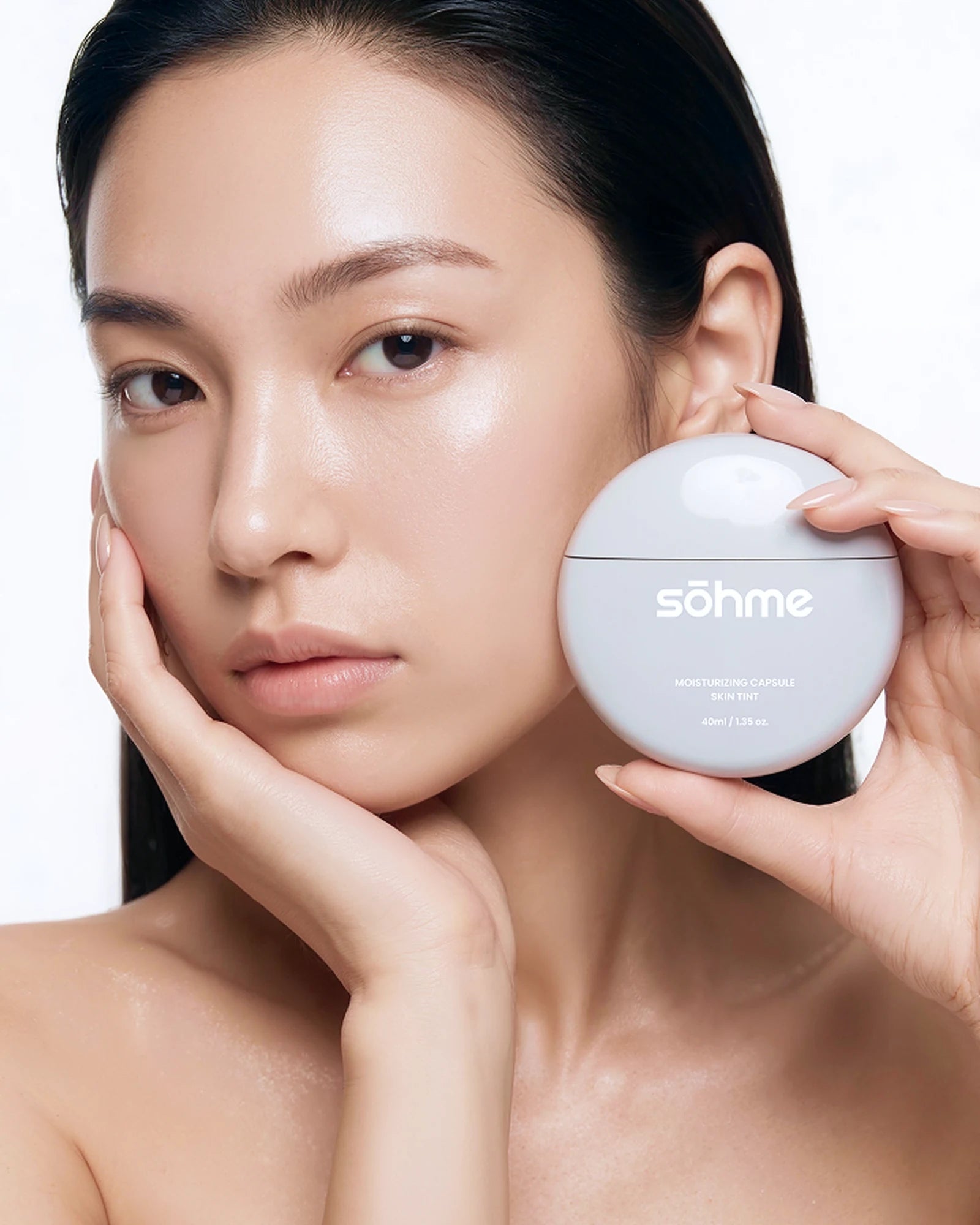 Modèle au teint lumineux tenant le pot de skin tint